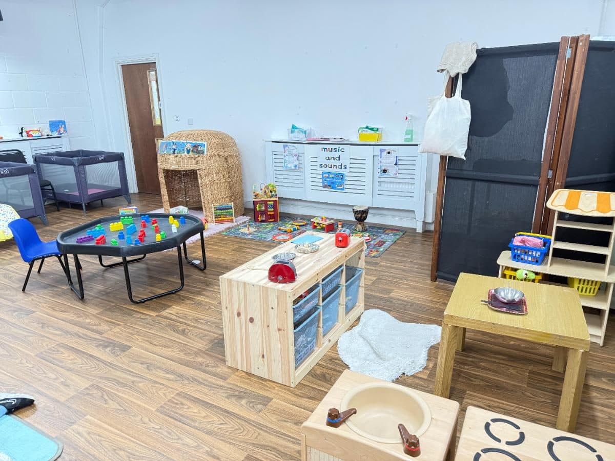 Destiny Haven Nursery playroom with colorful toys, trampoline, wooden furniture, and learning displays on white walls.