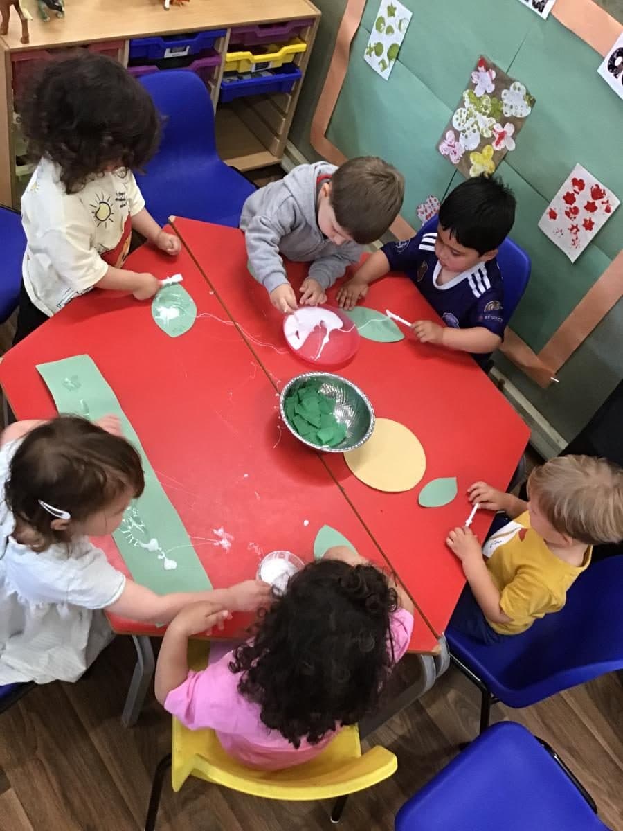 destiny haven nursery students sit around a red table engaged in a green