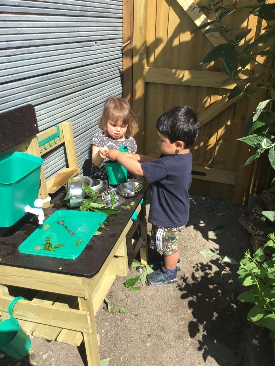 two young children engaged in outdoor play at destiny haven nurserys mud kitchen